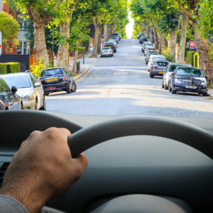 Image from drivers perspective with top of wheel in the foreground and road ahead, including signs, clearly visible, with distinct outlines and vivid colours to show significantly improved vision without cataracts/after cataract surgery