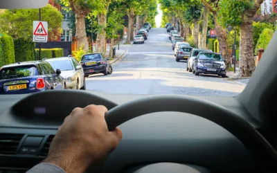 Image from drivers perspective with top of wheel in the foreground and road ahead, including signs, clearly visible, with distinct outlines and vivid colours to show significantly improved vision without cataracts/after cataract surgery