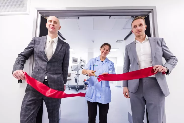 Woman cuts red ribbon with scissors to open surgery