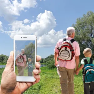 Someone on a walk, image showing phone in the foreground, view, and people walking ahead, clearly visible, with distinct outlines and vivid colours to show significantly improved vision without cataracts/after cataract surgery