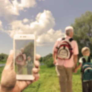 Someone on a walk, image showing blurred phone in the foreground, view, and people walking ahead, with colours dulled down to show vision with cataracts