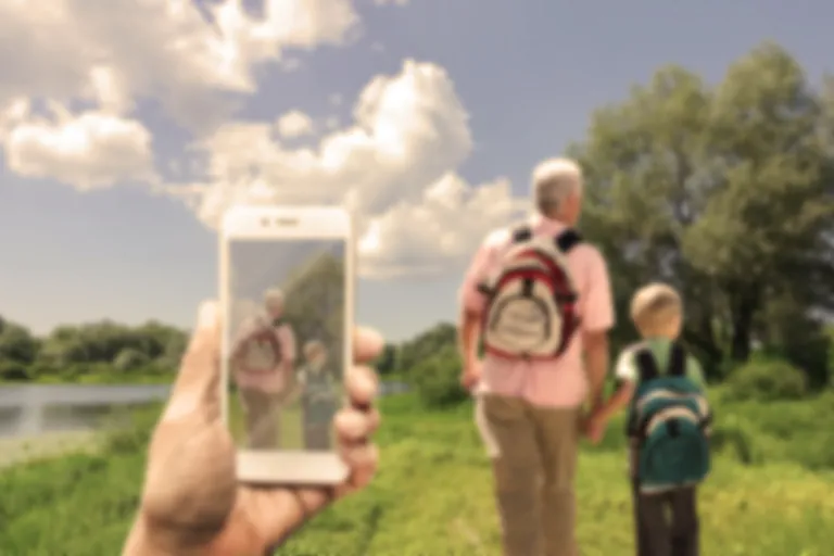 Someone on a walk, image showing blurred phone in the foreground, view, and people walking ahead, with colours dulled down to show vision with cataracts